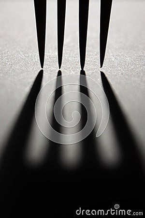 Harsh shadow cast by four fork prongs with sharp points Stock Photo