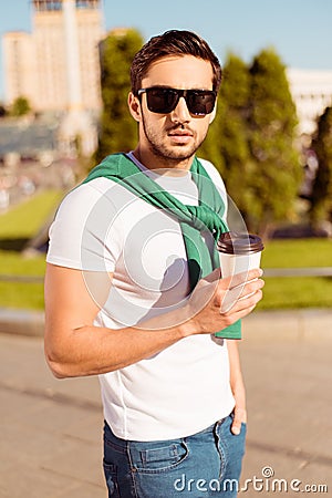 Harsh young brunete guy is having a coffee and walking in the ci Stock Photo