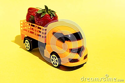 Harvest of fresh juicy strawberries is transported by a children`s toy truck. Stock Photo