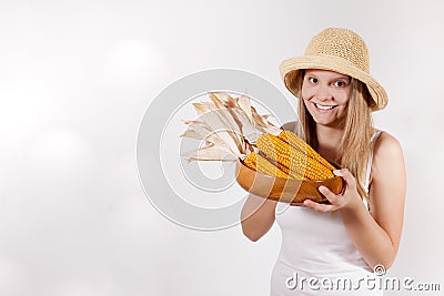 Harvest girl with hat is holding bowl with corn Stock Photo