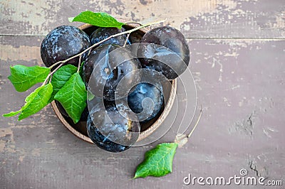 Harvest plums in a wooden dish on a wooden rustic background. Copy space. The view from the top Stock Photo