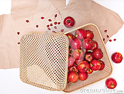 Harvest of ripe red apples lying in a wicker container, covered with a lid, against the background of rough paper Stock Photo