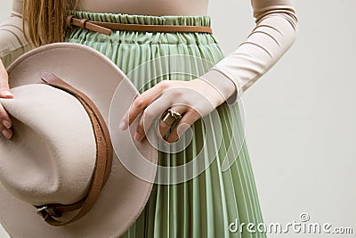 Hat, beige blouse and turqoise pleats skirt on light street backgraund. Stock Photo