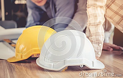 Hat engineers white and yellow on a wooden table. Stock Photo