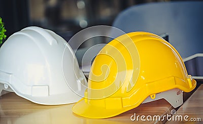 Hat engineers white and yellow on a wooden table. Stock Photo
