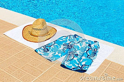 Hat and swimming trunks on towel near swimming pool Stock Photo