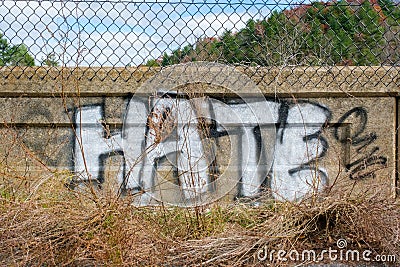 `Hate` graffiti painted on cement wall in large white capital letters. Editorial Stock Photo