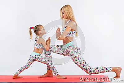 Hatha yoga fitness . Young mother and daughter exercise together indoors. Family look. Stock Photo