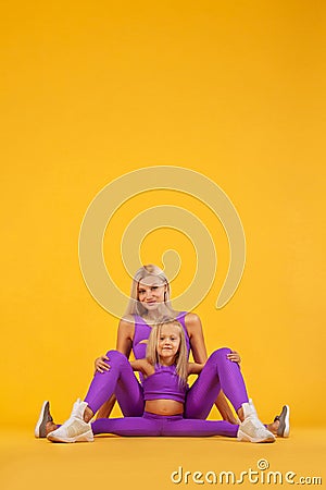 Hatha yoga fitness . Young mother and daughter exercise together indoors. Family look. Stock Photo