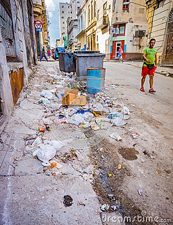 HAVANA, CUBA - OCT 28 - Man walks by piles of trash and garbage in the streets of Havana, Cuba on Oct 28, 2015 Editorial Stock Photo