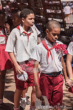 Havana, Cuba - Sept. 2018: The group of pupils in uniform, two boys going together on the front. Editorial Stock Photo