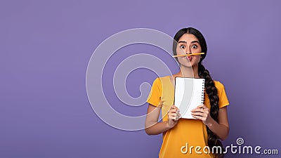 Funny indian lady holding pen as moustache over purple background Stock Photo