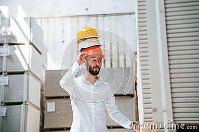 Having fun with hard hats. Storage worker is in the warehouse with bunch of products Stock Photo