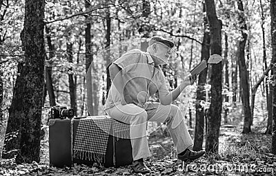 Having leisure to read more. Retired person read book in autumn nature. Old man read sitting on retro suitcase Stock Photo