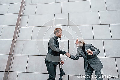 Having a meet. Young guy with senior man in elegant clothes is outdoors together. Conception of business Stock Photo