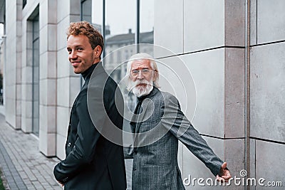 Having a meet. Young guy with senior man in elegant clothes is outdoors together. Conception of business Stock Photo