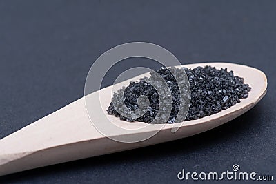 Hawaiian Black Lava Sea Salt in handmade wooden spoon on dark Stock Photo