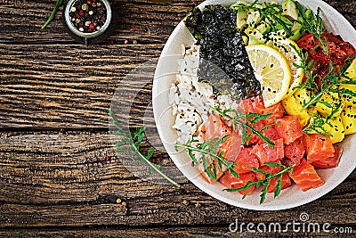 Hawaiian salmon fish poke bowl with rice, avocado, mango, tomato, sesame seeds and seaweeds. Stock Photo