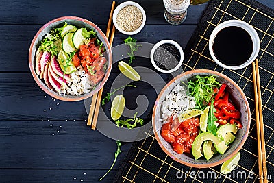 Hawaiian salmon fish poke bowl with rice, avocado, paprika, cucumber, radish, sesame seeds and lime. Buddha bowl. Diet food. Top Stock Photo