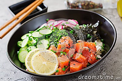 Hawaiian salmon fish poke bowl with rice, radish,cucumber, tomato, sesame seeds and seaweeds. Stock Photo