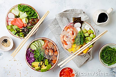 Hawaiian salmon, tuna and shrimp poke bowls with seaweed, avocado, mango, pickled ginger, sesame seeds. Stock Photo