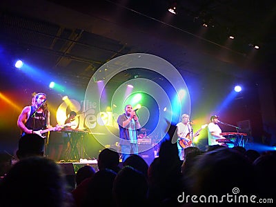 Hawaiian Style band the Green sing into mic while playing instruments to make music at concert Editorial Stock Photo