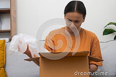 Haywire female client inspects box of goods holding filler for transportation safety at home Stock Photo