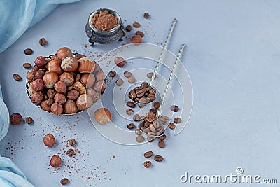 Hazelnut, coffee beans and cocoa powder in light blue background Stock Photo