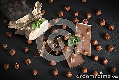 Hazelnuts, chocolate and a jar of nuts on a black board Stock Photo
