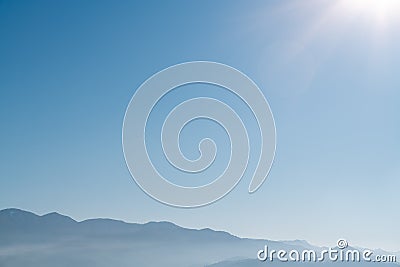 Hazy foggy mountain silhouettes with aerial perspective against a clear blue sky Stock Photo