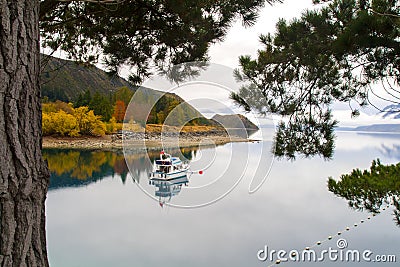 Peaceful autumn landscape, solitary holiday boat on the calm waters, pristine mountain lake, mirror water reflection, New Zealand Stock Photo