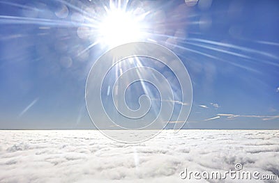 HDR photo of an airplane wing against the blue sky with a cloud cover underneath and brigh shining sun in in front of it Stock Photo