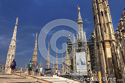 HDR photo of he white marble statues and decorations on the Cathedral Duomo di Milano on piazza in Milan with visitors Editorial Stock Photo