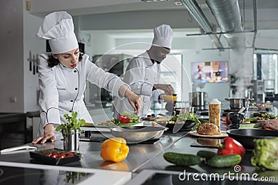 Head chef cooking food for dinner service while adding ingredients to meal. Stock Photo