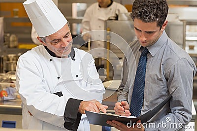 Head chef and waiter discussing menu Stock Photo