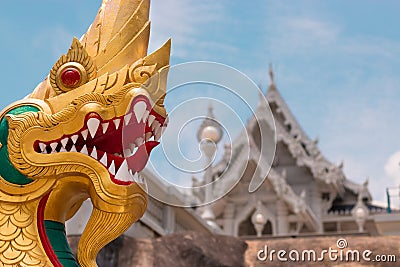 The head of a golden dragon against the background of the white Buddhist temple Wat Kaew Korawaram Editorial Stock Photo