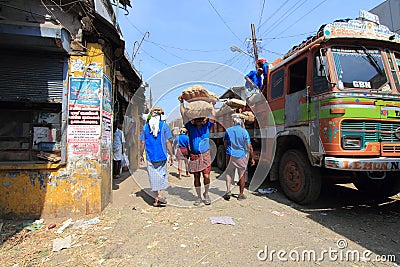 Head load workers unloading gunny bags from a truck in the market Editorial Stock Photo