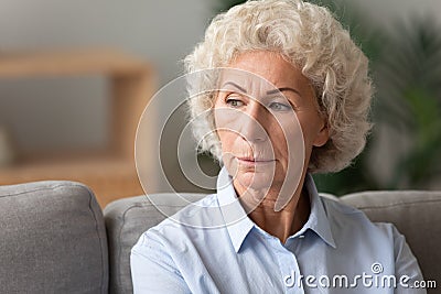 Head shot older woman lost in thoughts, sitting on couch Stock Photo