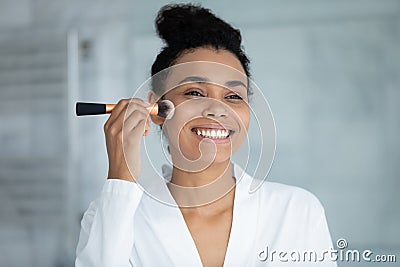 Head shot smiling African American woman using cosmetics brush Stock Photo