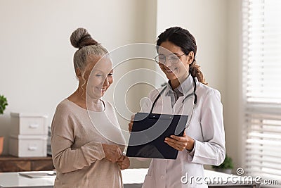 Head shot smiling doctor consulting mature patient, holding clipboard Stock Photo