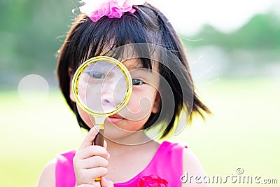 Head shot. Cute Asian child girl looking through gold selling glasses. Kid aged 4-5 years old Stock Photo