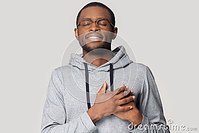 Head shot grateful African American man holding hands on chest Stock Photo