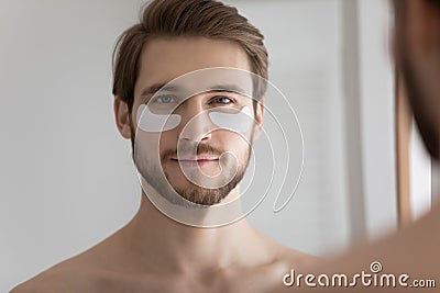 Head shot mirror reflection young man with hydrogel eye patches Stock Photo