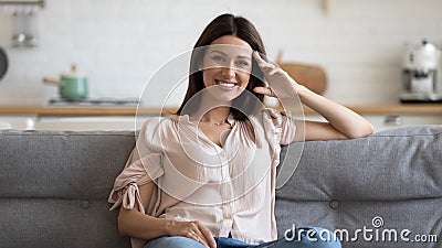 Happy 30s woman sitting on cozy sofa in living room. Stock Photo