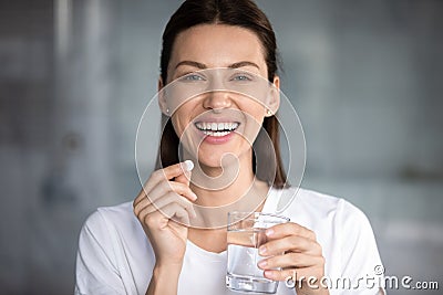 Cheerful woman holding pill glass of water looking at camera Stock Photo