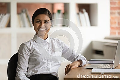 Head shot portrait smiling Indian businesswoman sitting at work desk Stock Photo