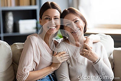 Head shot portrait smiling young woman hugging mature mother Stock Photo