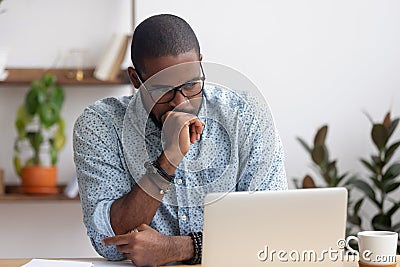 Head shot serious puzzled African American businessman looking at laptop Stock Photo