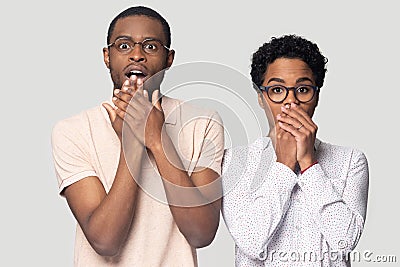 Head shot shocked African American couple covering mouths with hands Stock Photo