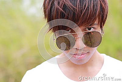 Head shot of Thai male teenager in white t-shirt and sunglasses is staring at camera. Stock Photo